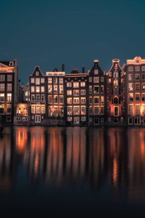 Photo for A vertical shot of beautiful Amsterdam waterfront buildings under the blue sky at night - Royalty Free Image