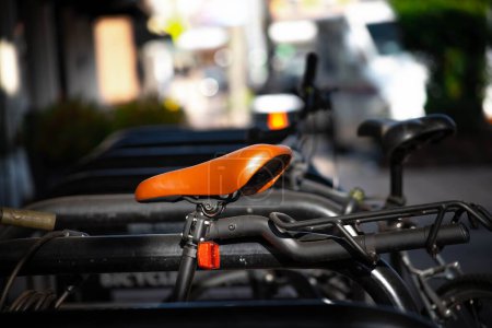 Foto de Un enfoque selectivo de un asiento de bicicleta naranja estacionado al aire libre sobre el fondo borroso - Imagen libre de derechos