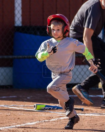 Téléchargez les photos : Gros plan vertical d'un jeune enfant jouant au baseball courant vers la première base après un coup - en image libre de droit