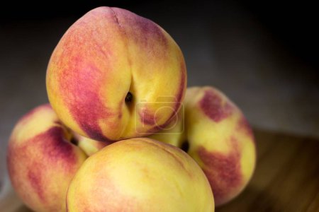 Photo for A closeup of the four juicy peaches on a bamboo cutting board - Royalty Free Image