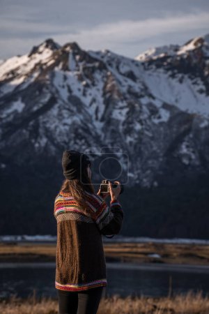 Téléchargez les photos : Plan vertical d'une jeune femme photographiant la montagne enneigée des hauts plateaux - en image libre de droit