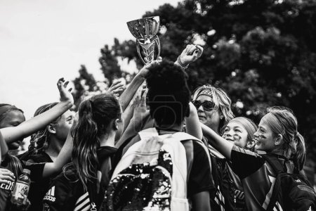 Foto de Una escala de grises del equipo Freedom Courage Youth Women 's Soccer elevando un trofeo recién ganado en el aire - Imagen libre de derechos
