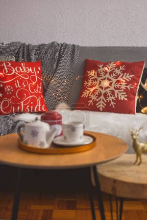 Téléchargez les photos : Un plan vertical d'un ensemble de thé sur un plateau sur la table avec des décorations de Noël sur le canapé - en image libre de droit