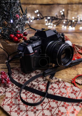 Foto de Una toma vertical de una vieja cámara de cine sobre la mesa de madera decorada con adornos navideños - Imagen libre de derechos
