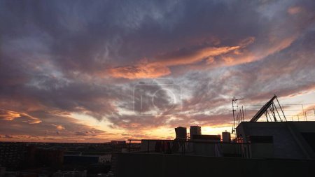 Téléchargez les photos : Les silhouettes des bâtiments de la ville sous le ciel nuageux du coucher du soleil - en image libre de droit