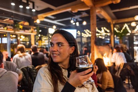 Foto de Hermosa chica bebiendo cerveza oscura en una noche en el bar - Imagen libre de derechos