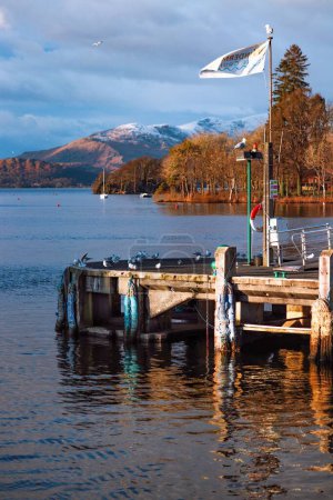 Téléchargez les photos : Plan rapproché d'un quai en bois au bord du lac contre des montagnes enneigées dans le Lake District, Royaume-Uni - en image libre de droit