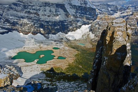 Téléchargez les photos : Vue aérienne d'un petit lac entourant des montagnes rocheuses couvertes de neige sous des nuages enneigés - en image libre de droit