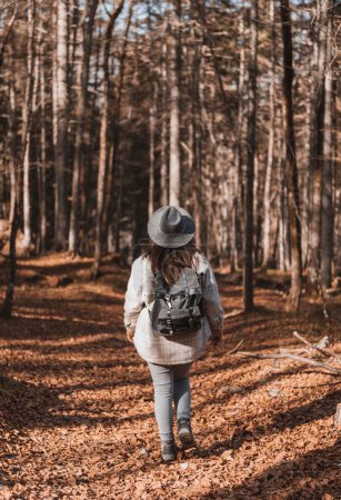 Téléchargez les photos : Sac à dos et chapeau pour femme, randonnée en forêt en automne - en image libre de droit
