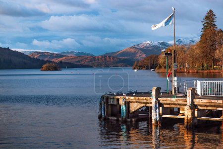 Téléchargez les photos : Plan rapproché d'un quai en bois au bord du lac contre des montagnes enneigées dans le Lake District, Royaume-Uni - en image libre de droit
