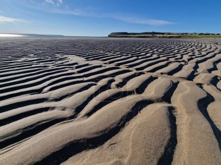 Téléchargez les photos : Les ondulations de sable sous la lumière du soleil contre le ciel bleu par un jour lumineux - en image libre de droit