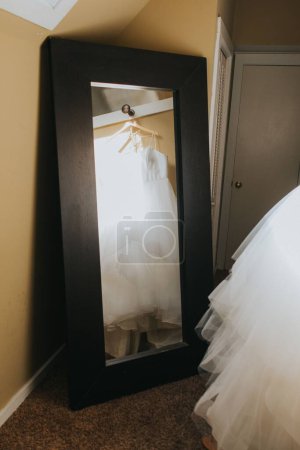 Téléchargez les photos : Une verticale des mariées belle robe blanche pendue devant un miroir - en image libre de droit