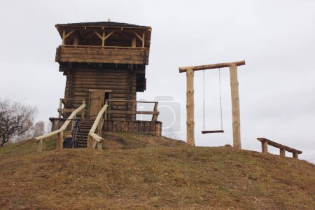 Téléchargez les photos : Château de Krevo. Tour de guet en bois, balançoire et banc sur la montagne Yury par temps nuageux - en image libre de droit