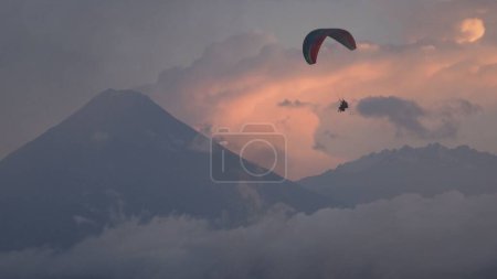Téléchargez les photos : Une belle vue sur les gens parapente dans le ciel avec la grande montagne en arrière-plan sur le ciel couchant - en image libre de droit