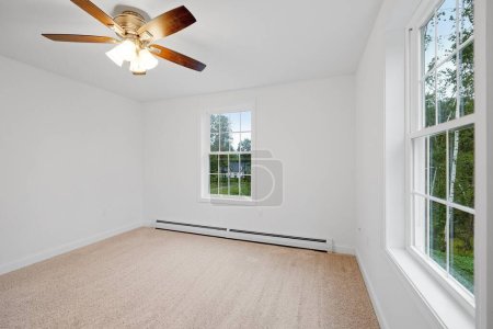 Téléchargez les photos : Une pièce dans une maison nouvellement construite avec des murs blancs, un lustre éclairé et des fenêtres en verre - en image libre de droit