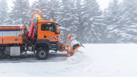 A side view of a snowplow at work in the Grosser Feldberg in Germany with thick trees around it