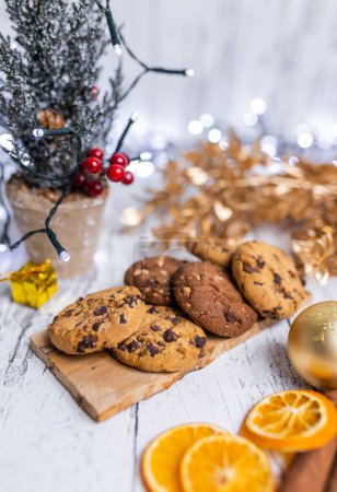 Foto de Un plano vertical de las galletas de chispas de chocolate servidas en la mesa decoradas con adornos navideños - Imagen libre de derechos