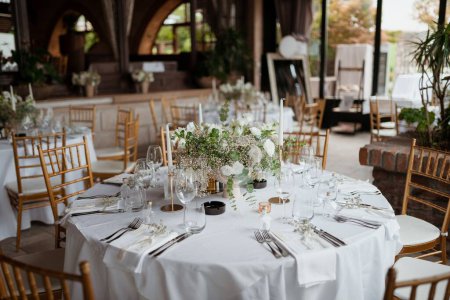 Foto de Una mesa bellamente decorada con flores blancas ramo y velas y muchas sillas - Imagen libre de derechos