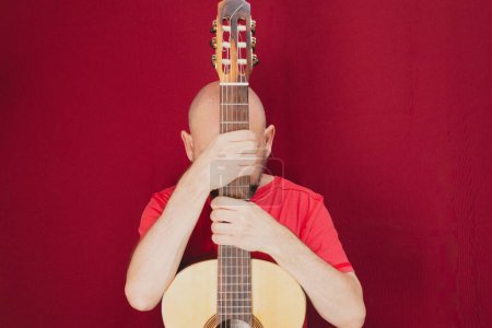 Foto de Un guitarrista masculino carismático aislado sobre un fondo rojo - Imagen libre de derechos