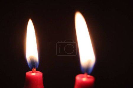 Foto de Un primer plano de dos velas rojas ardiendo en la oscuridad - Imagen libre de derechos