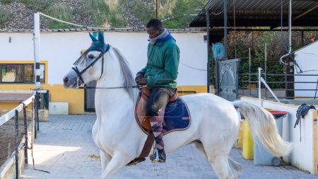Foto de Un jinete masculino montando un caballo blanco para entrenar - Imagen libre de derechos