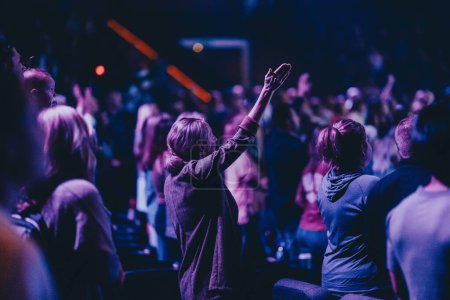 Téléchargez les photos : Un groupe de personnes dans le culte de l'église avec des effets de lumière bleue et violette - en image libre de droit