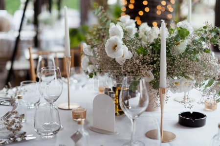 Téléchargez les photos : Un gros plan d'une table magnifiquement décorée avec bouquet de fleurs blanches et bougies - en image libre de droit