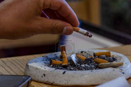 Téléchargez les photos : Gros plan d'un jeune homme fumant sur une table en bois - en image libre de droit