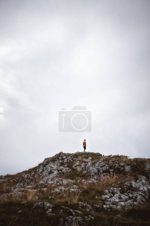 Foto de Un disparo vertical de un hombre de pie en la cima de la montaña Durmitor en Zabljak, Montenegro - Imagen libre de derechos