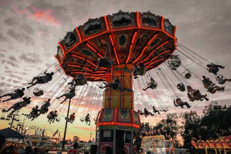 Photo for A low-angle California state fair carnival ride and a lot of people enjoying their time at sunset cloudy purple sky background - Royalty Free Image