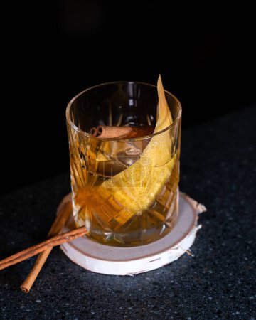 Téléchargez les photos : Un cocktail whisky avec une tranche d'orange et un bâton de cannelle à l'intérieur. - en image libre de droit