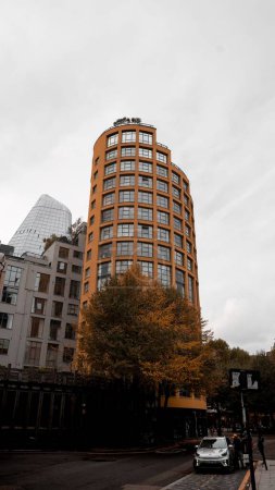 Foto de Un plano vertical del moderno edificio circular amarillo con un diseño único bajo el cielo nublado - Imagen libre de derechos