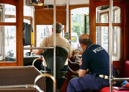 Photo for The inside of a historical tram line 28 lisbon with a driver and police officer - Royalty Free Image