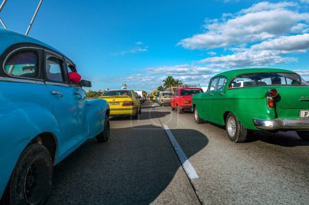 Photo for A long line of cars stopped next to the sea in a road under a sunny day, the foreground with American classic cars, people waiting at the side - Royalty Free Image