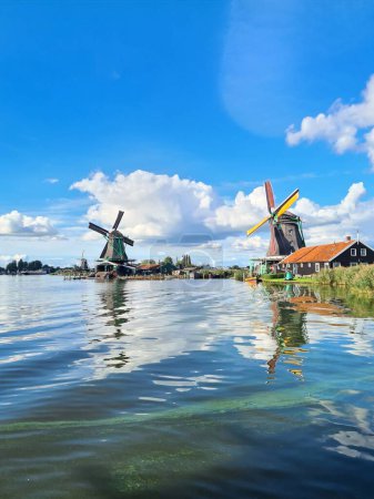 Photo for A vertical shot of the windmills at the shore in the green countryside - Royalty Free Image