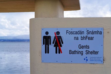 Téléchargez les photos : Signez à l'entrée de Gents Bathing Shelter sur Bull Island à Dublin. Texte bilingue rédigé en irlandais et en anglais. Concept public de ségrégation sexuelle. - en image libre de droit