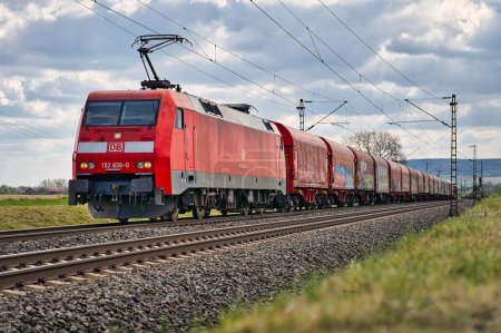 Téléchargez les photos : Un train Retzbach Zellingen 152 sur le chemin de fer avec un champ en arrière-plan par une journée sombre - en image libre de droit