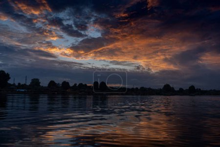 Téléchargez les photos : Une belle vue sur un coucher de soleil reflété dans le lac Dal avec des arbres luxuriants au loin à Srinagar, en Inde - en image libre de droit