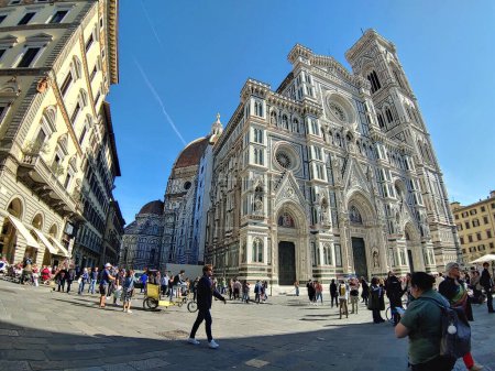 Photo for A low angle shot of Giotto's Bell Tower surrounded by tourists under the blue sky, Florence - Royalty Free Image