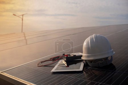 Foto de Casco de un ingeniero con un dispositivo de medición de corriente colocado en un panel solar en el sol de la noche - Imagen libre de derechos