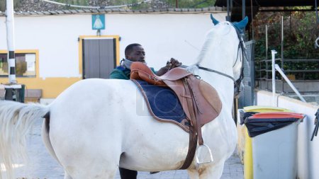 Foto de Un jinete macho montando un caballo blanco para entrenar - Imagen libre de derechos