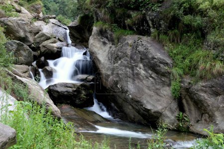 Téléchargez les photos : Une vue panoramique d'une cascade coulant sur les rochers couverts de verdure - en image libre de droit