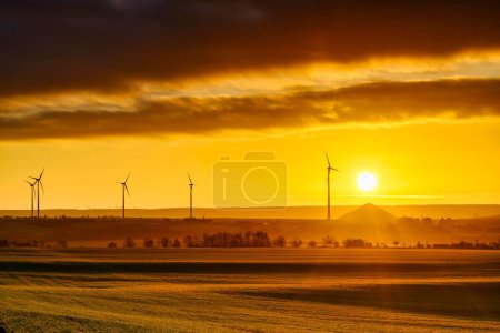 Foto de Salida del sol con vistas a turbinas eólicas y montones mineros desde las minas de cobre en el sur de las montañas Harz - Imagen libre de derechos