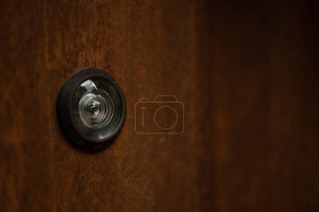 A closeup of the peephole on the wooden door