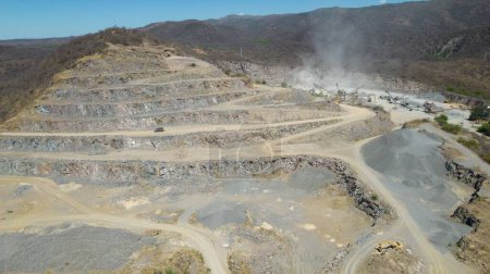 Téléchargez les photos : Vue aérienne d'une carrière de ciment dans une région montagneuse et poussière provenant des machines de travail - en image libre de droit
