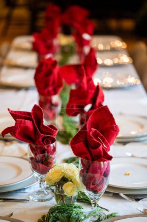 Foto de Un disparo vertical de ramos de flores y servilletas rojas en vasos que decoran la mesa de bodas - Imagen libre de derechos