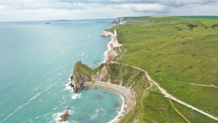 Photo for An aerial of Lulworth Cove with green grass and seascape aeound cloudy sky background - Royalty Free Image