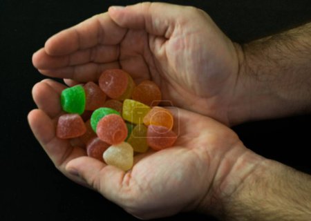 Foto de Las manos masculinas sosteniendo caramelos coloridos - Imagen libre de derechos