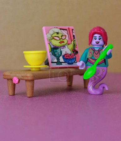 Téléchargez les photos : Plan vertical d'un jouet personnage de poulpe femelle cuisinant dans une cuisine avec une cuillère et une peinture - en image libre de droit