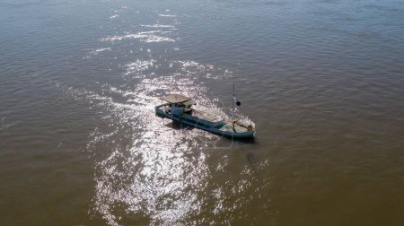 Foto de Un disparo aéreo de una barcaza de draga que elimina la arena del río en la superficie del mar brillante - Imagen libre de derechos
